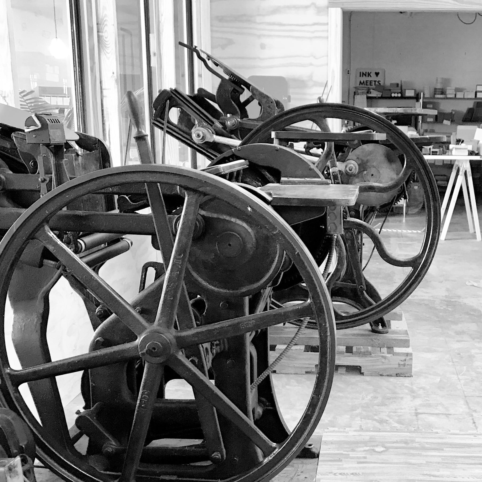 Black & white image showing antique printing presses in the press room at the studio.