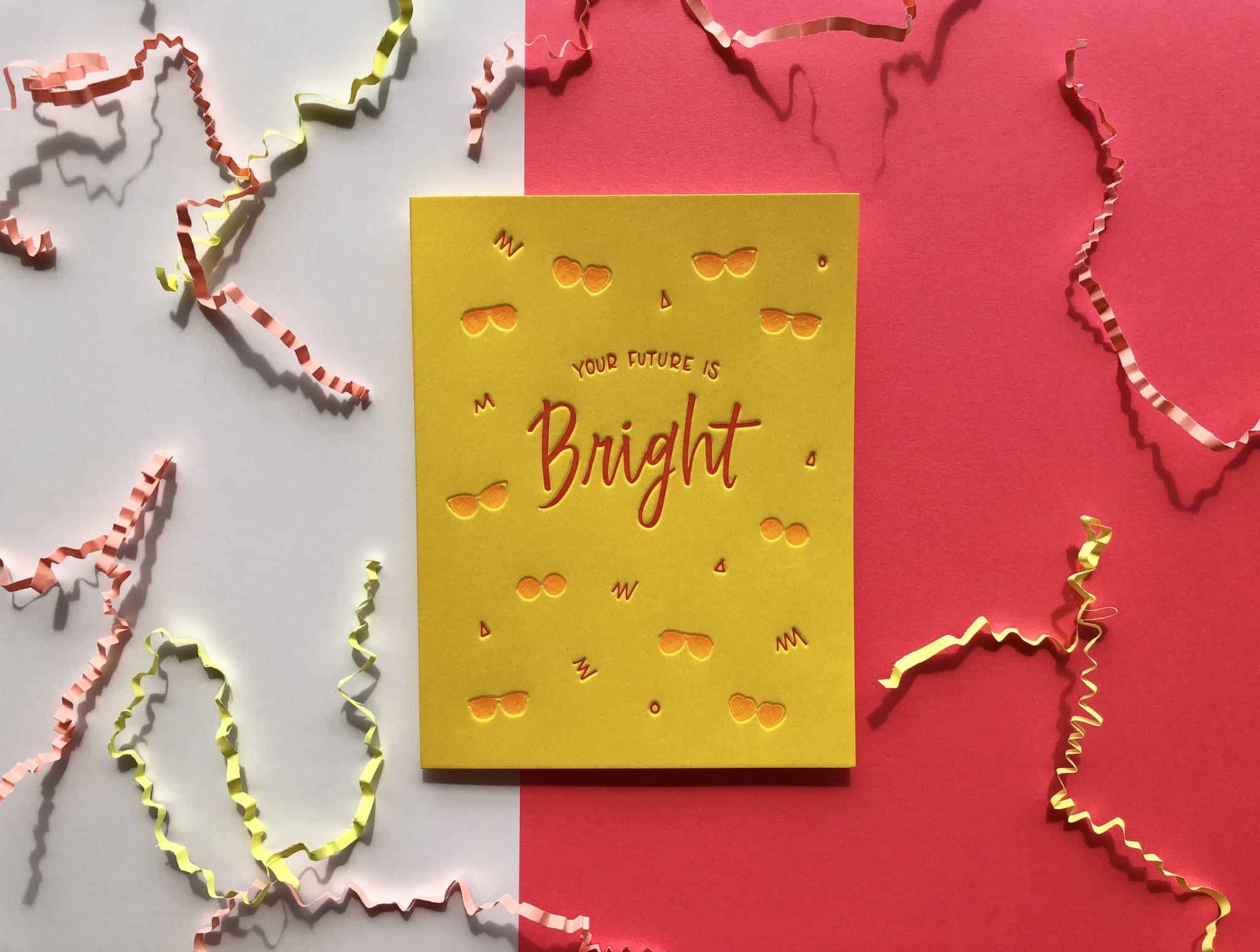 Yellow greeting card on coral and white background with zig-zag paper shred.