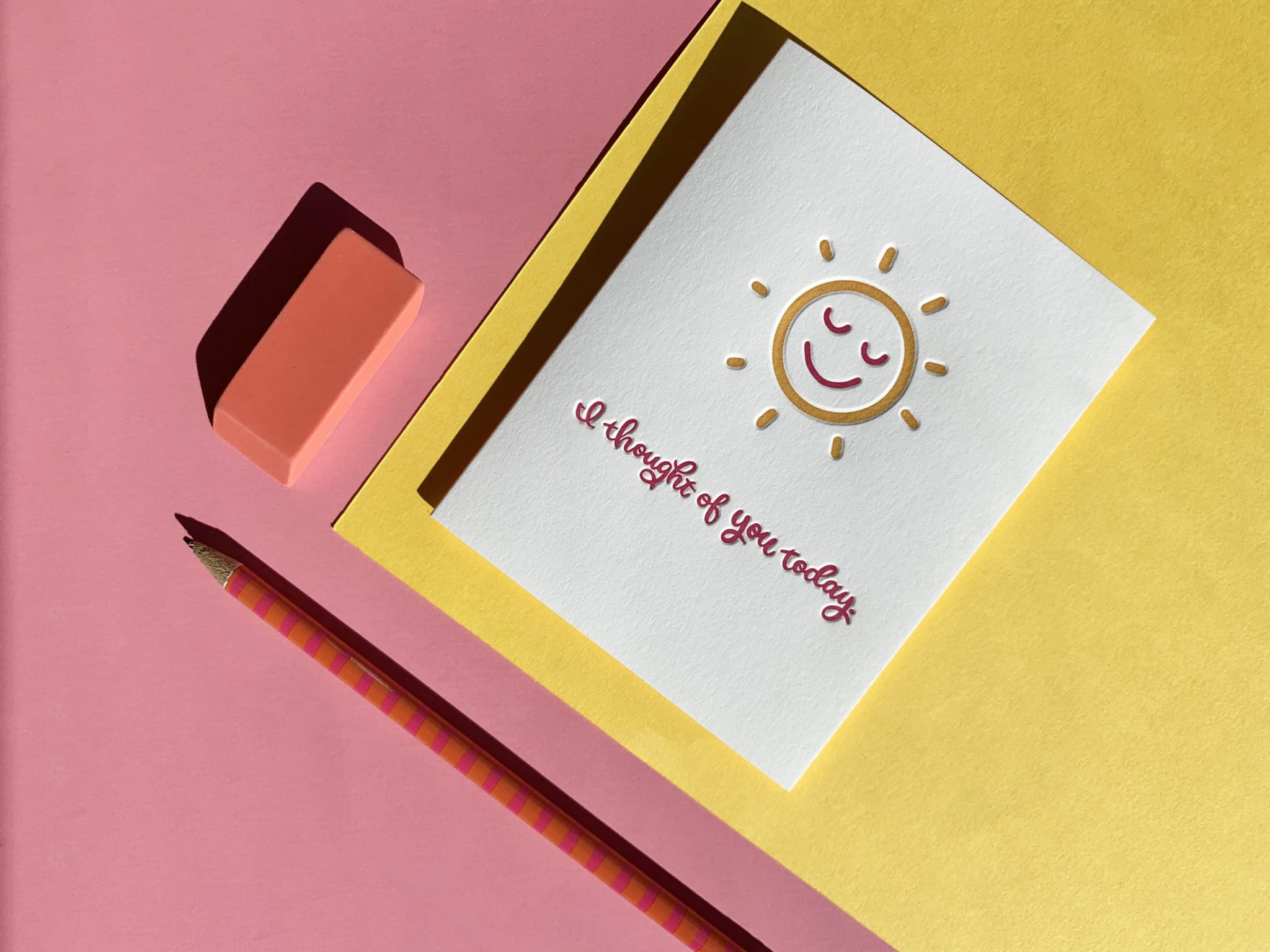 a hand-drawn, smiling, sunshine highlights this letterpress greeting card, as it is paired with a colored pencil and eraser over a bright layered-paper background