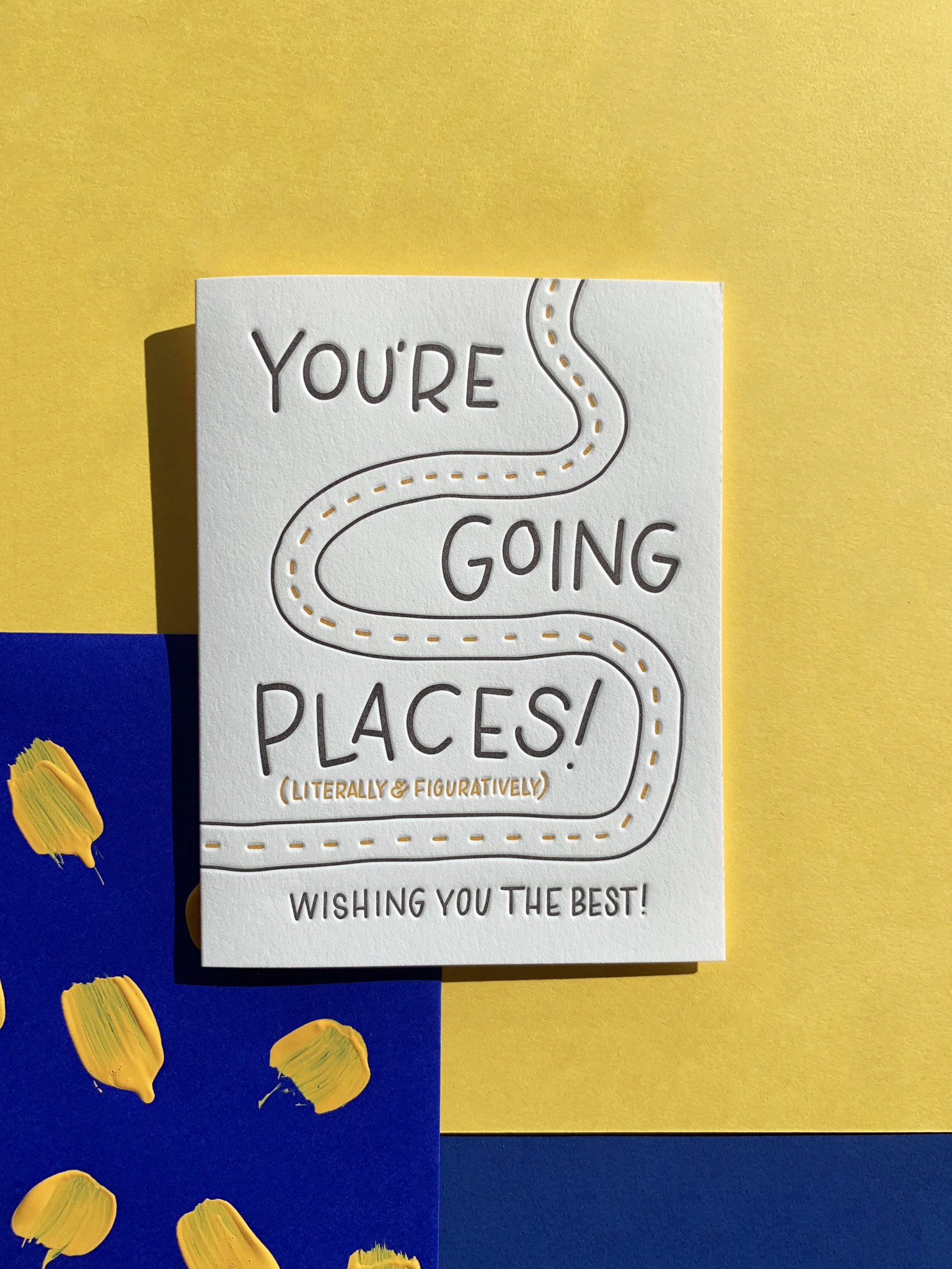 You're Going Places greeting card on layered yellow & blue paper background.