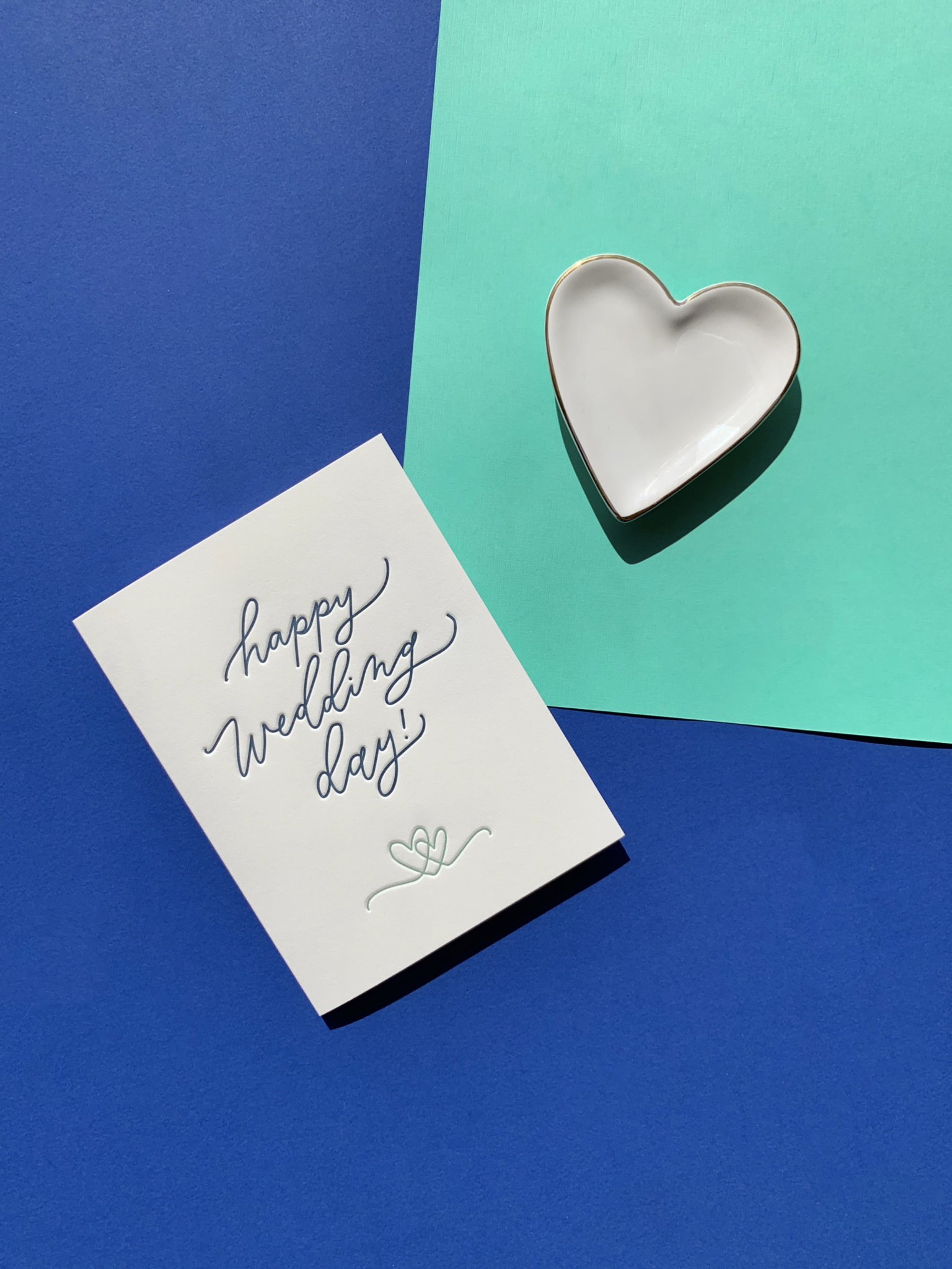 Wedding letterpress greeting card on layered paper background with heart ceramic dish accent