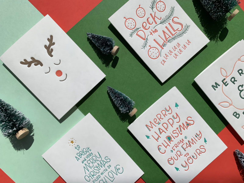 New Holiday cards laid out in a grid over layered paper background.
