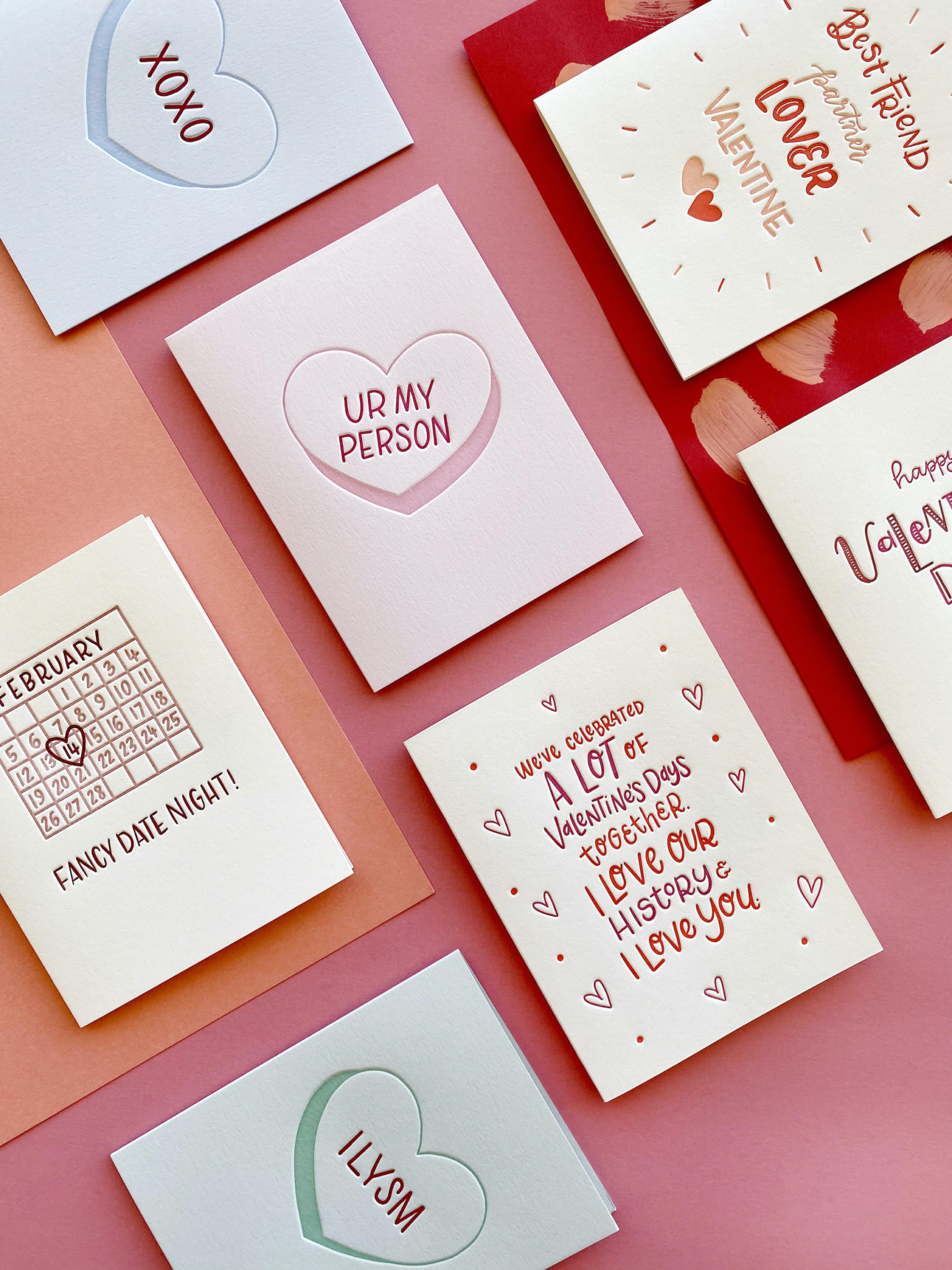 Greeting cards in a Valentine's Day color-scheme flat-layed on paper background.