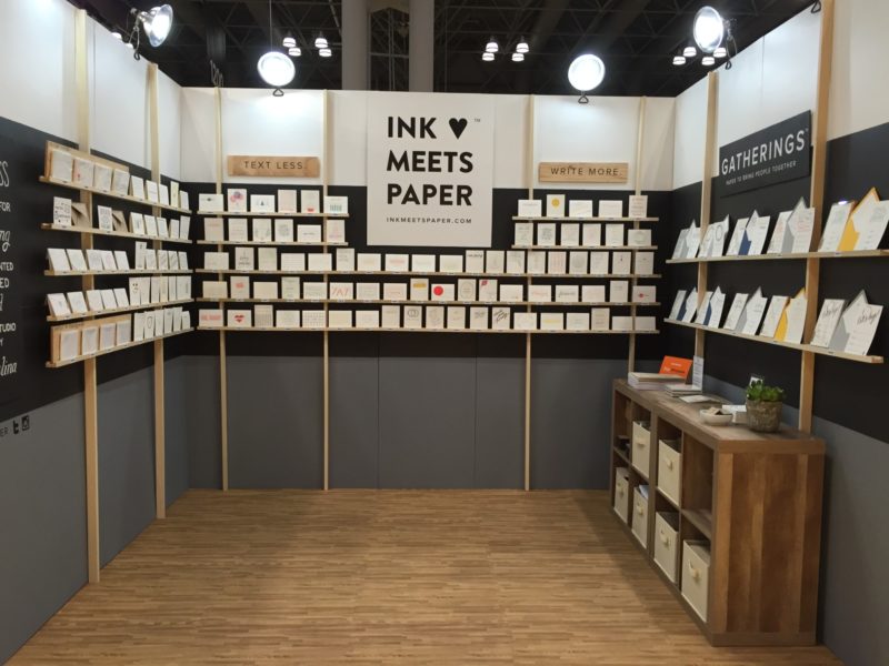 Trade show booth with greeting cards on shelves mounted to three walls