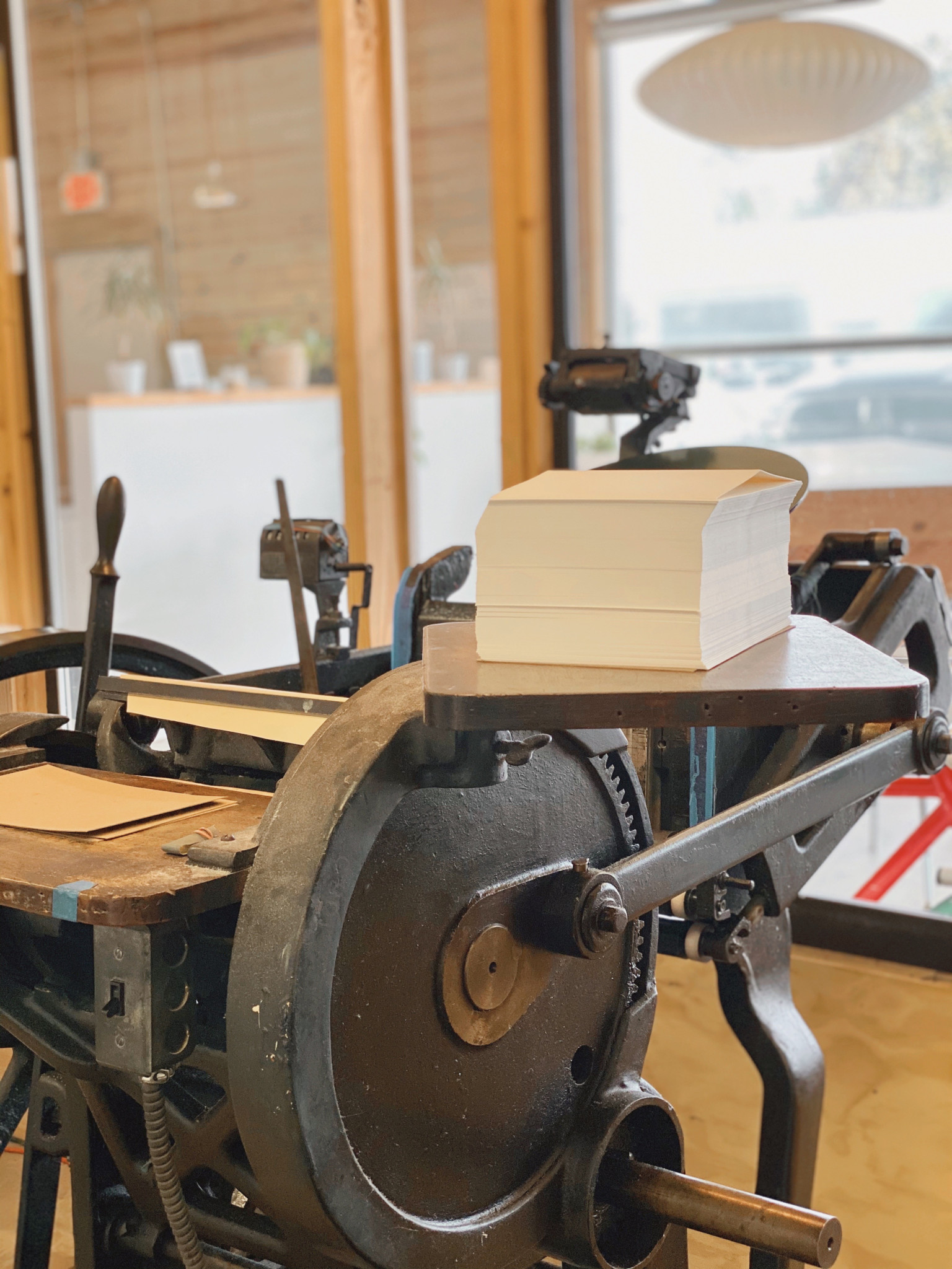 A stack of paper rests on the feed board of the antique printing press.