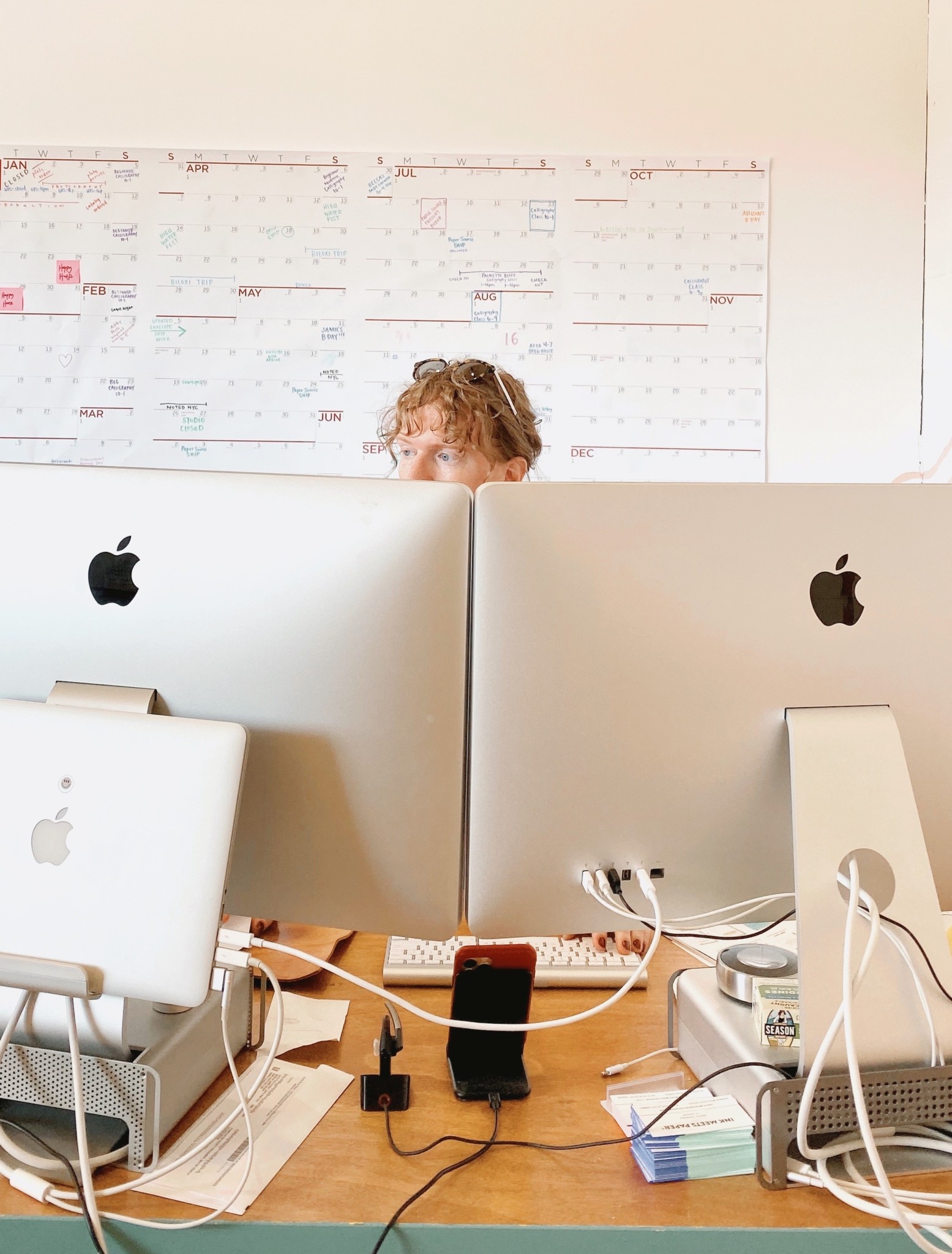 Jamie Nadeau sits at her desk behind two large computer monitors.