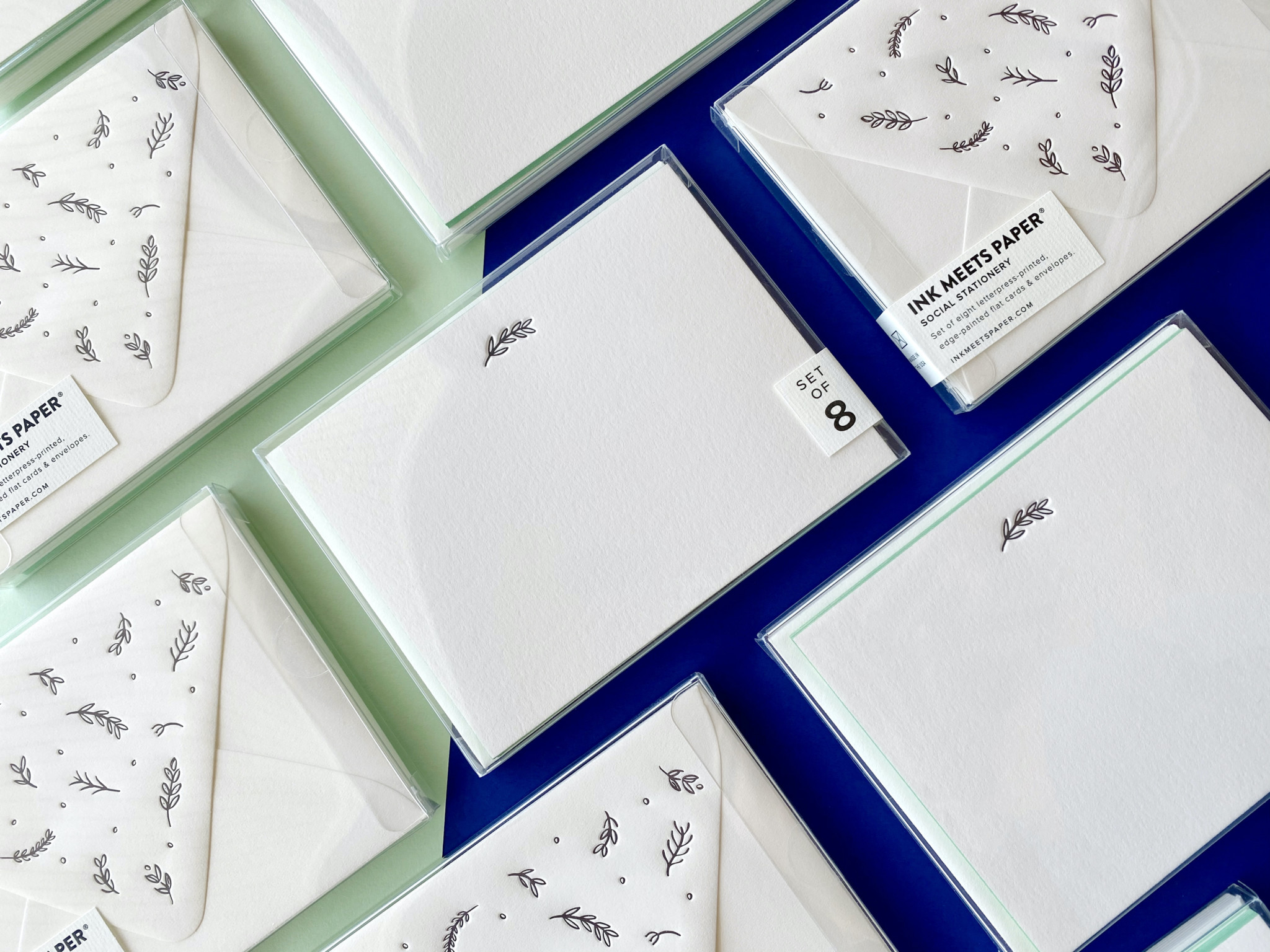 Botanics social stationery boxed sets laid out in grid over layered paper background