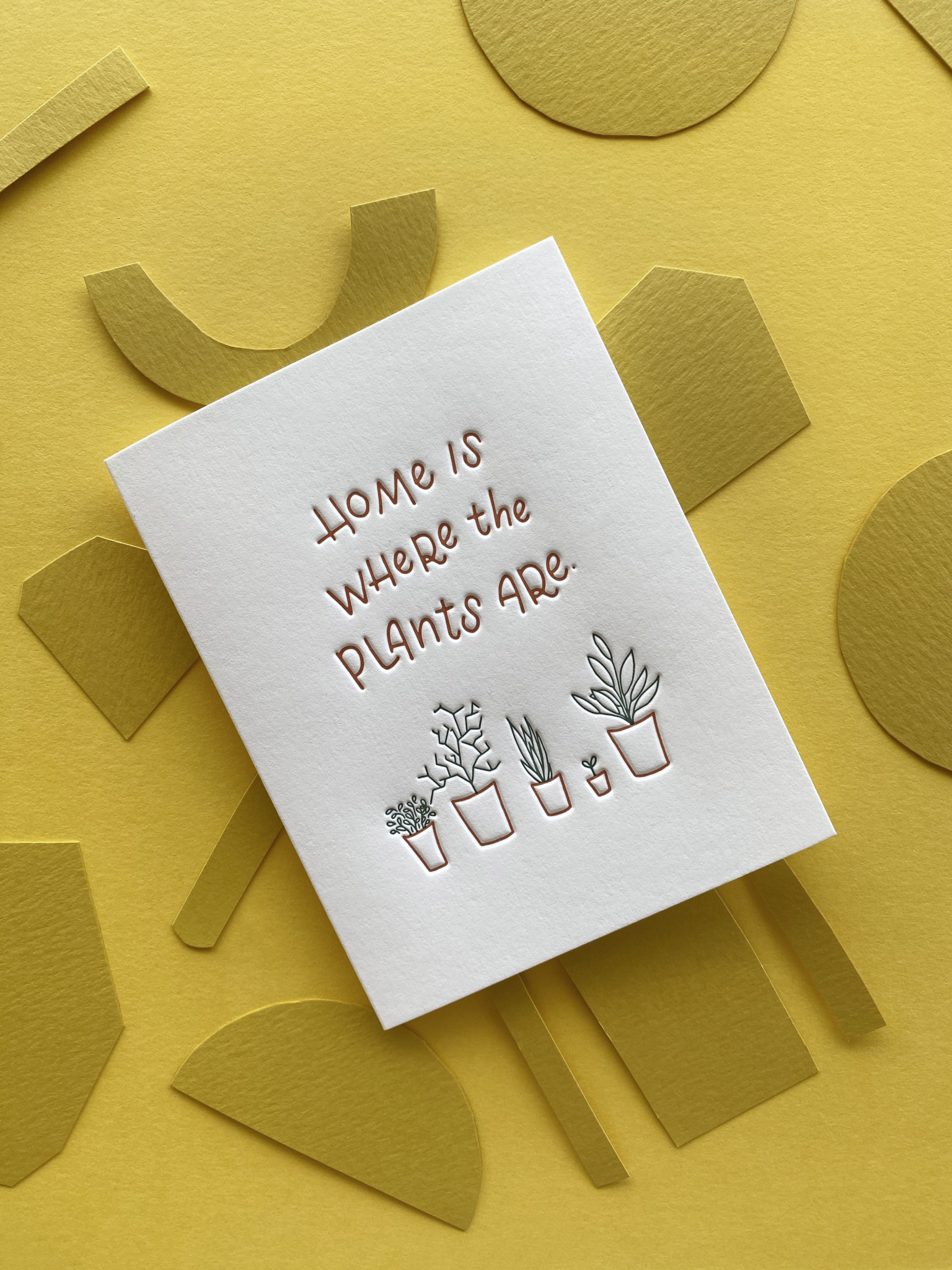 Home is where the plants are greeting card on layered paper yellow background.