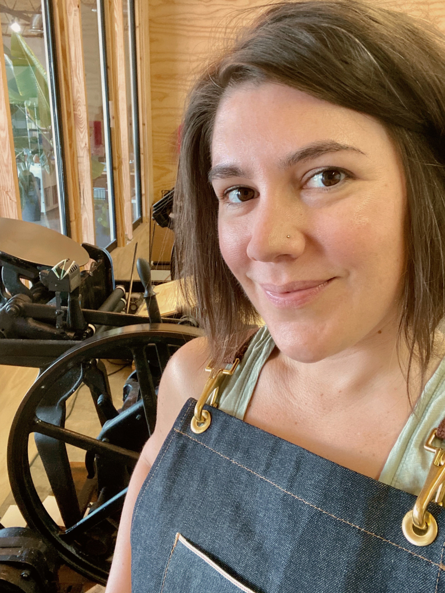 Allison standing in foreground with printing press in background.