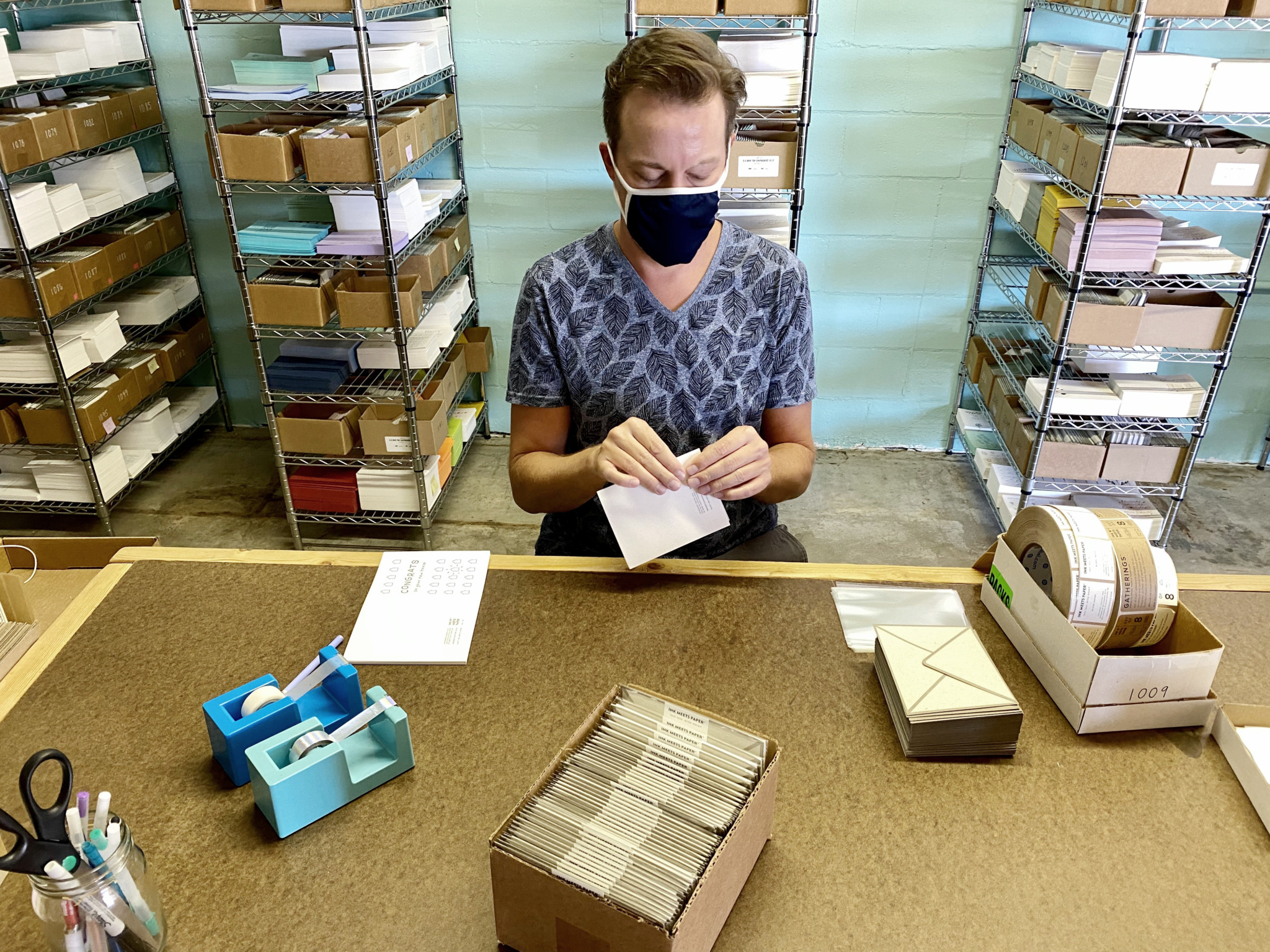 Team member assembles paper goods with shelves of paper goods in the background.