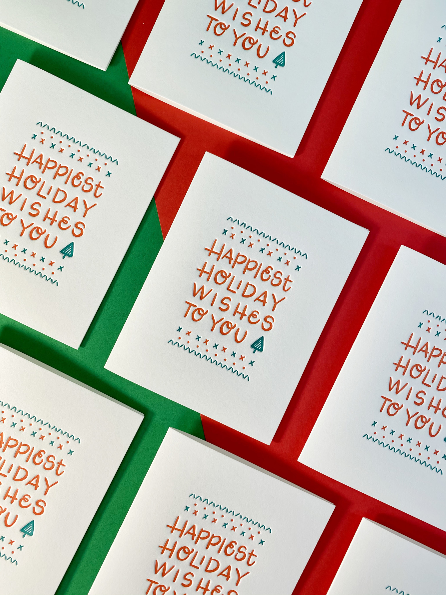 Grid of greeting cards in the same style over red & green background. Card reads, "Happiest Holiday Wishes to You"